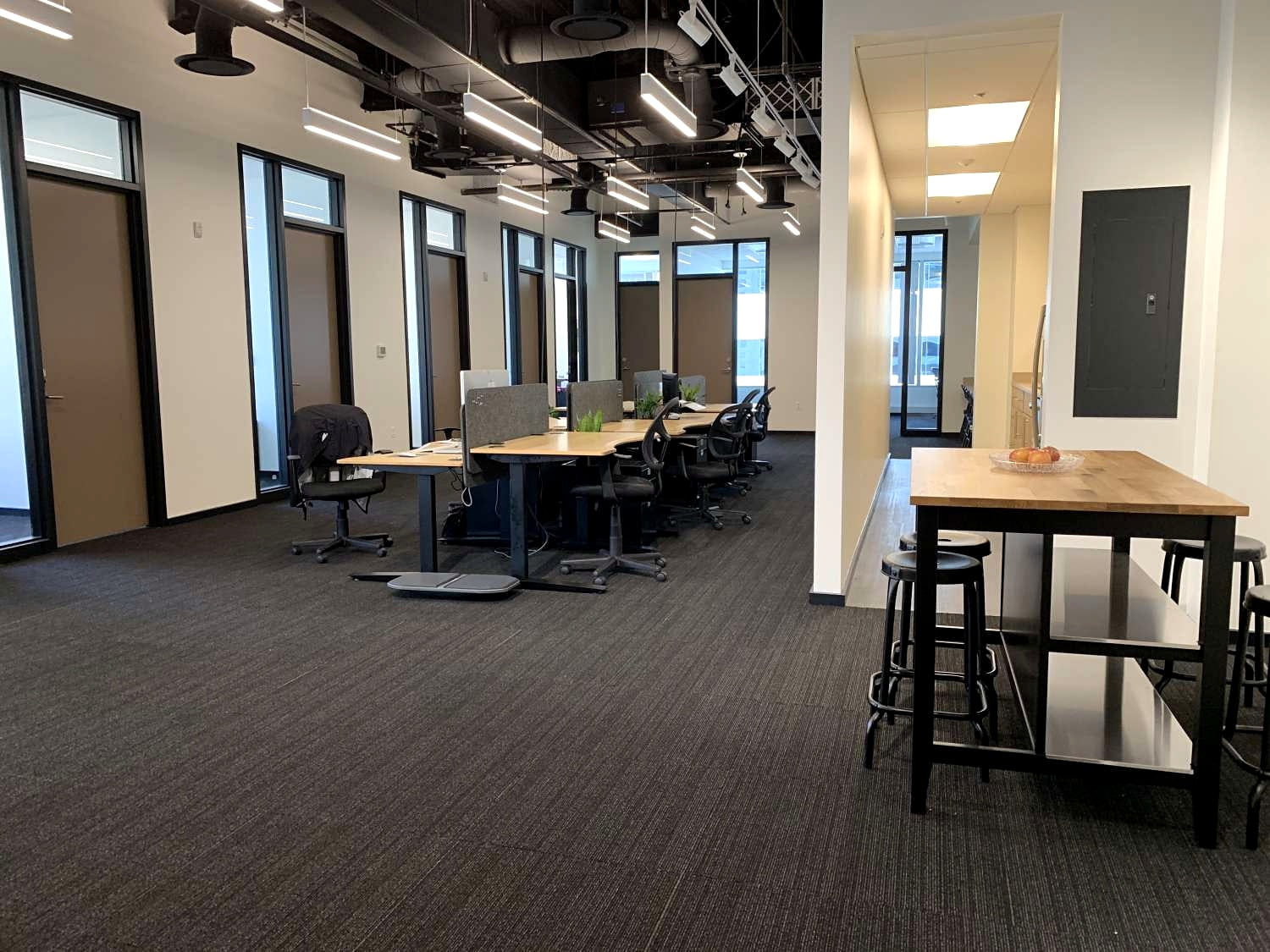 The open floor at Pratt Street, desks set as separate tables with the glass offices behind